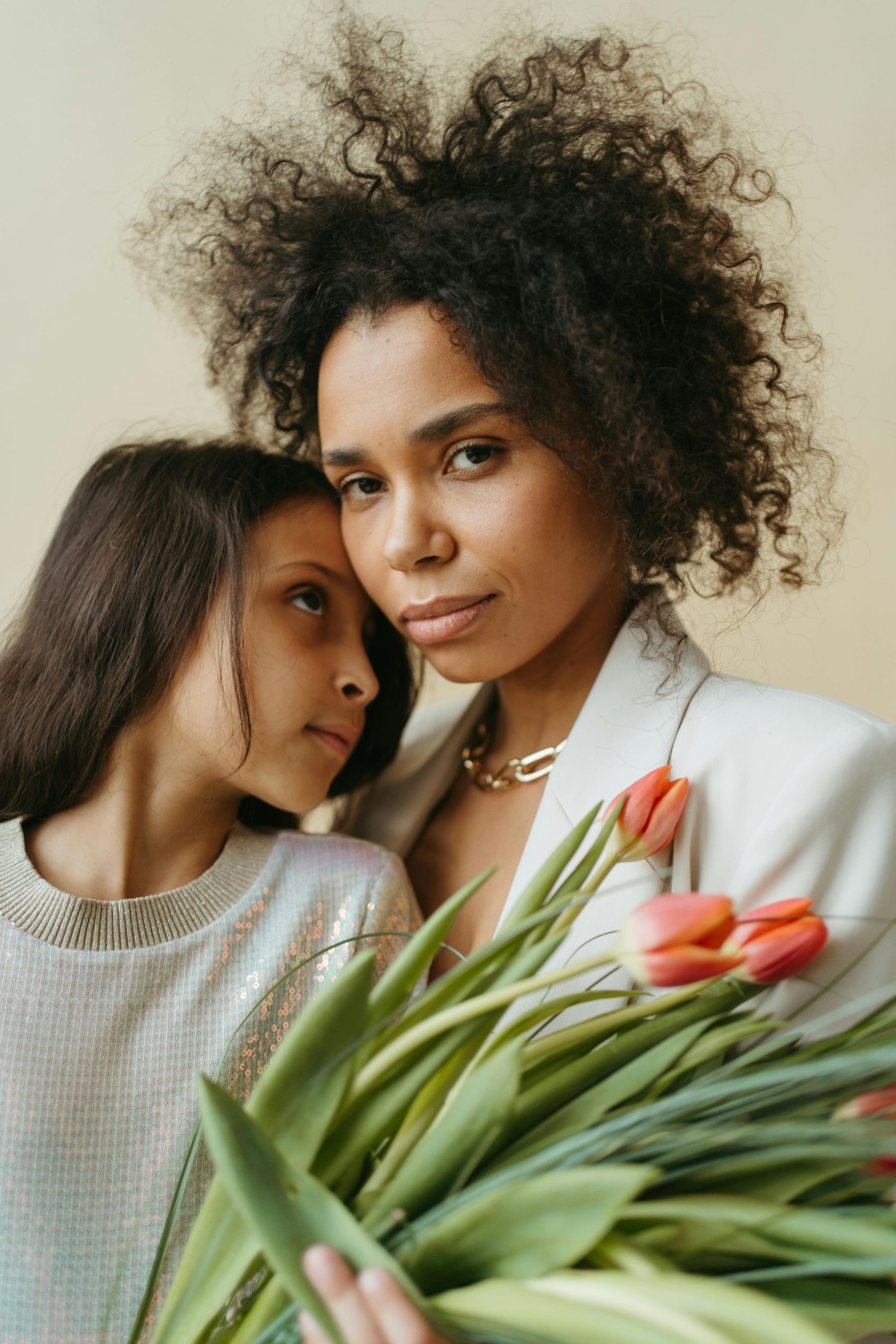 A tender moment between a mother and daughter holding vibrant tulips indoors.